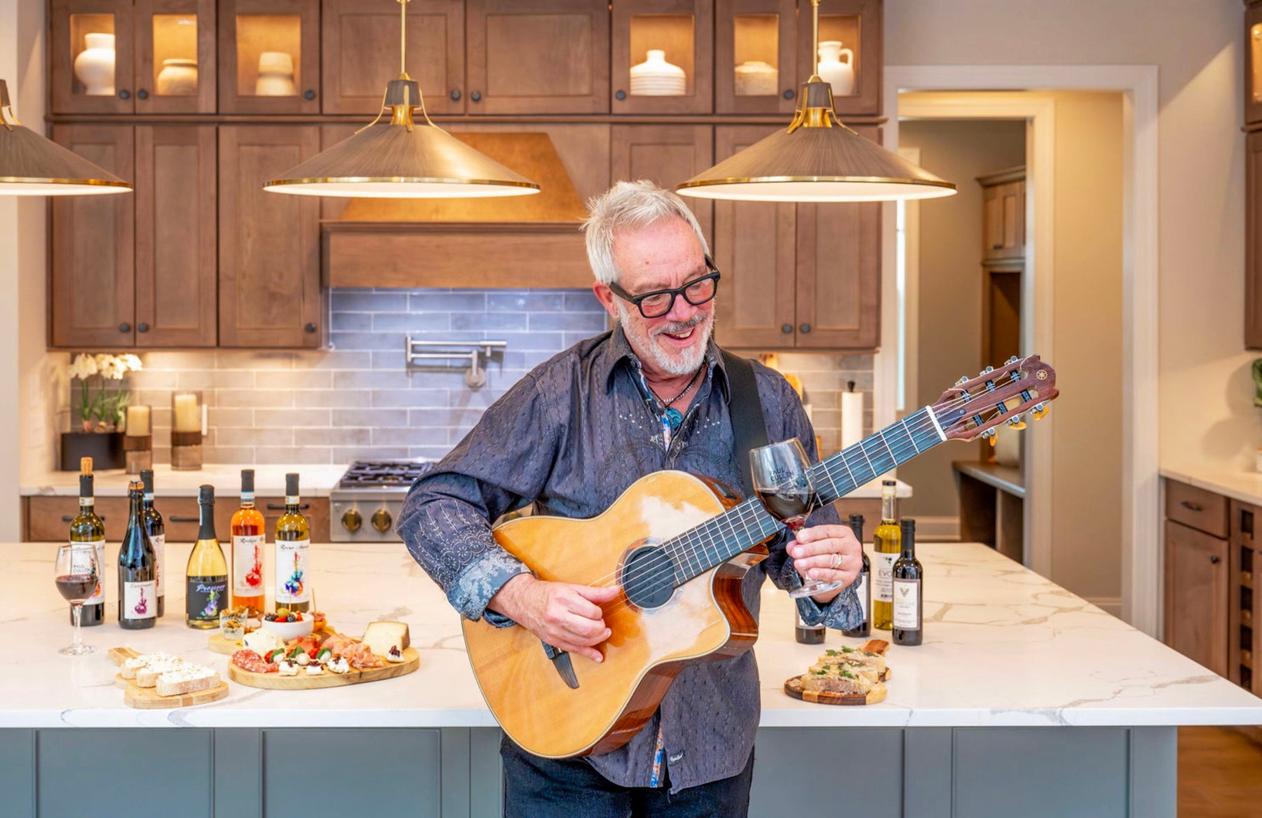 Paul Cullen playing guitar with wine in his kitchen