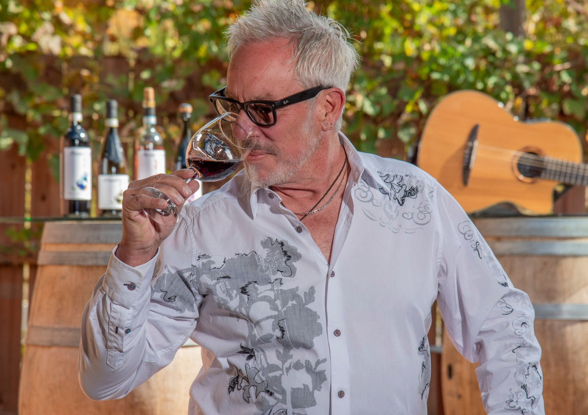 Paul Cullen tasting wine with his guitar and wine collection